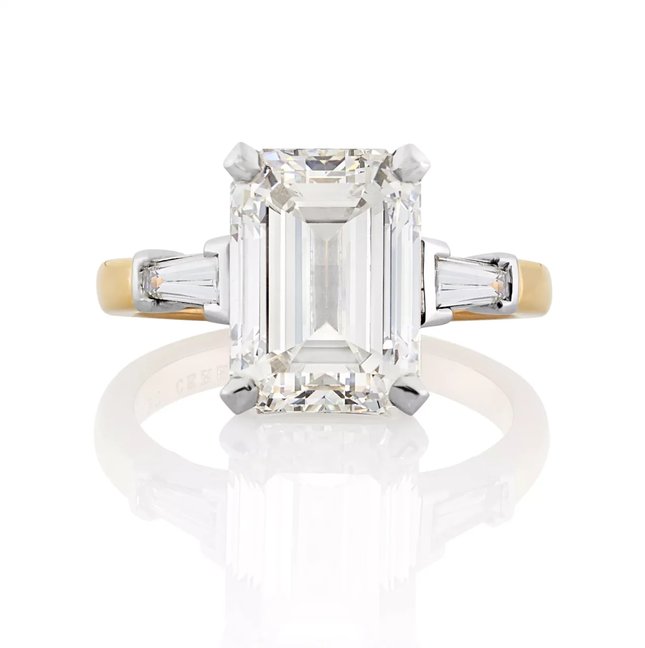 Platinum and rose gold emerald and tapered baguette trilogy engagement ring